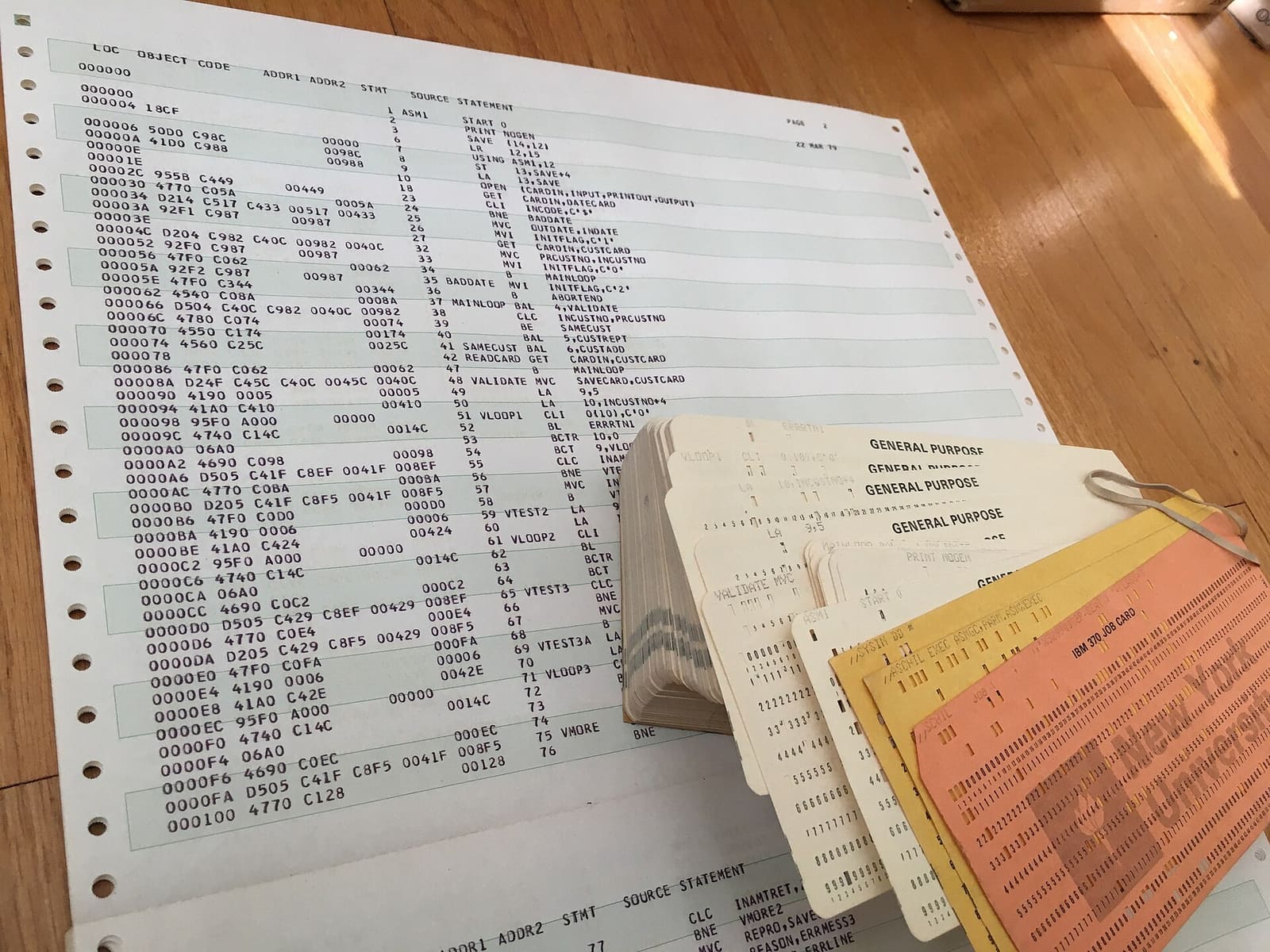 A printed program listing with line numbers next to a stack of punched cards
