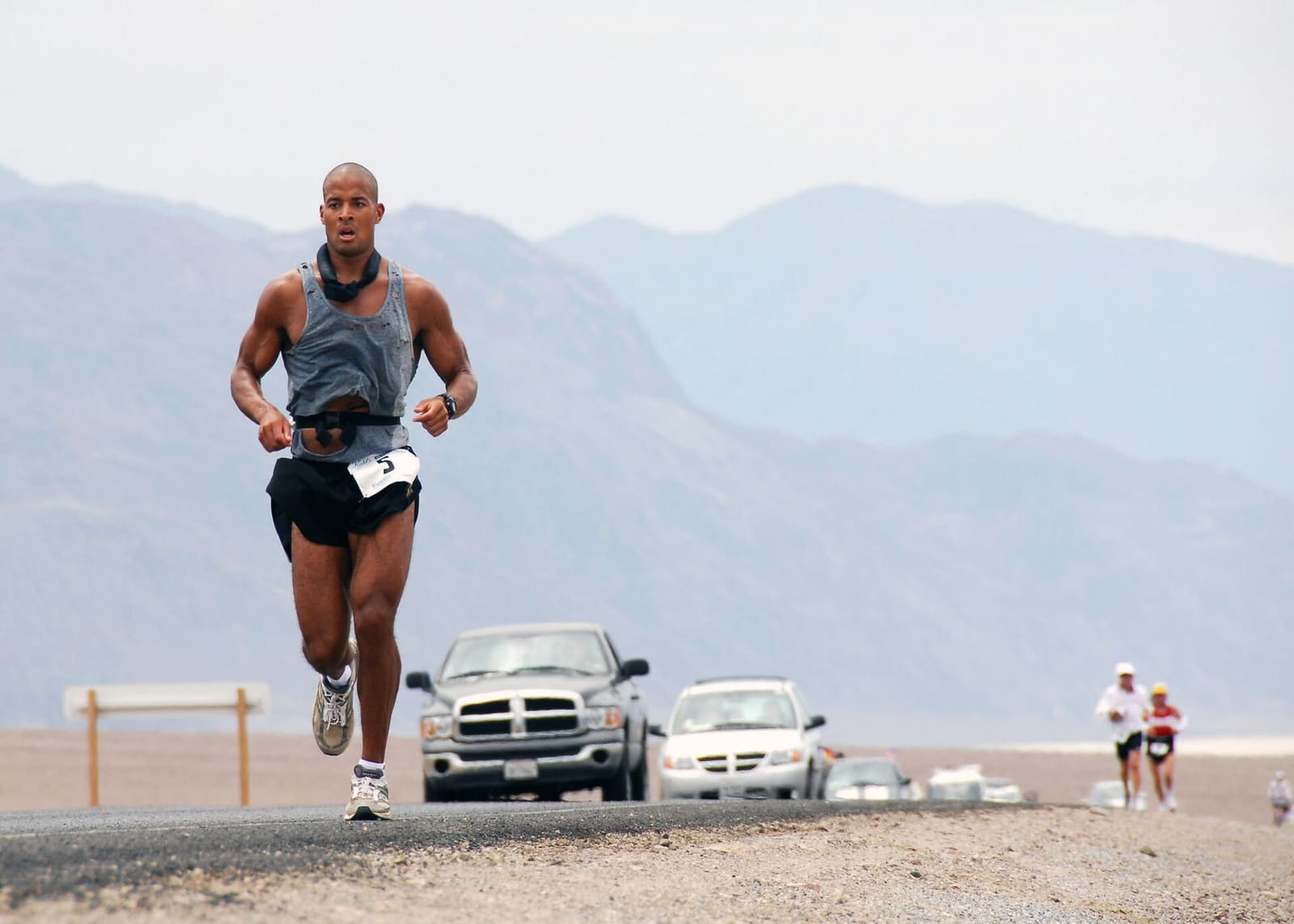 A runner on a desert road in Death Valley during the Badwater ultramarathon, with mountains behind him