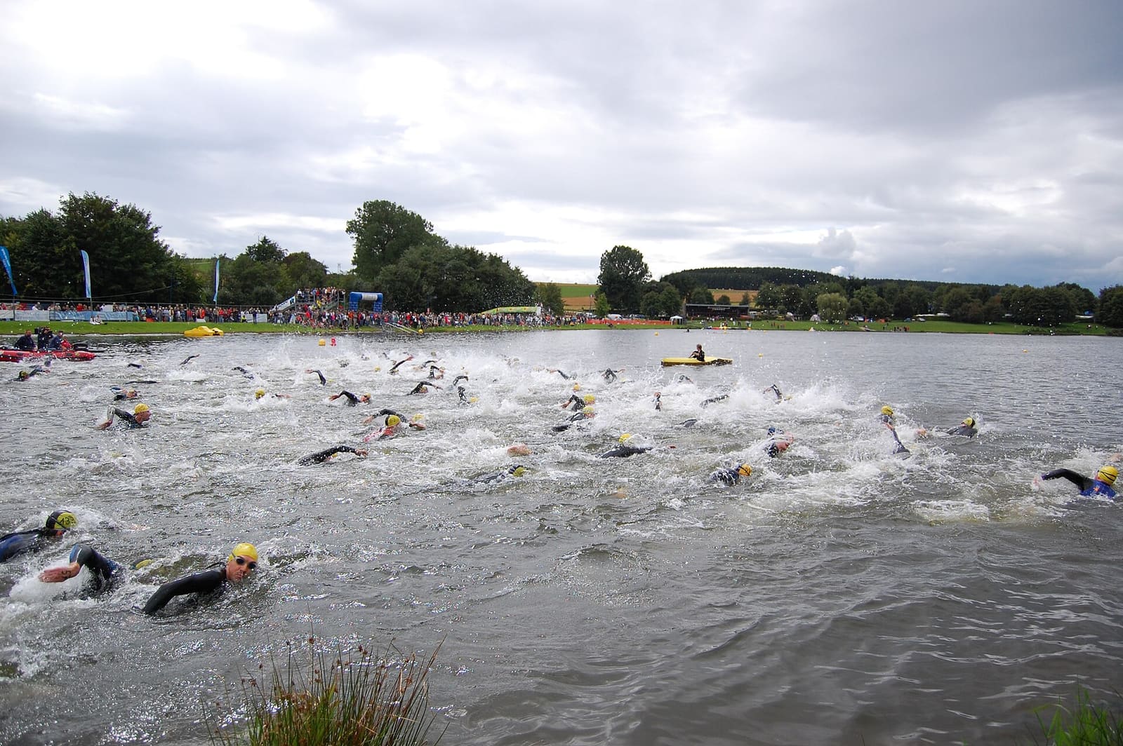 Triathletes in wetsuits and swim caps starting the swim leg in open water