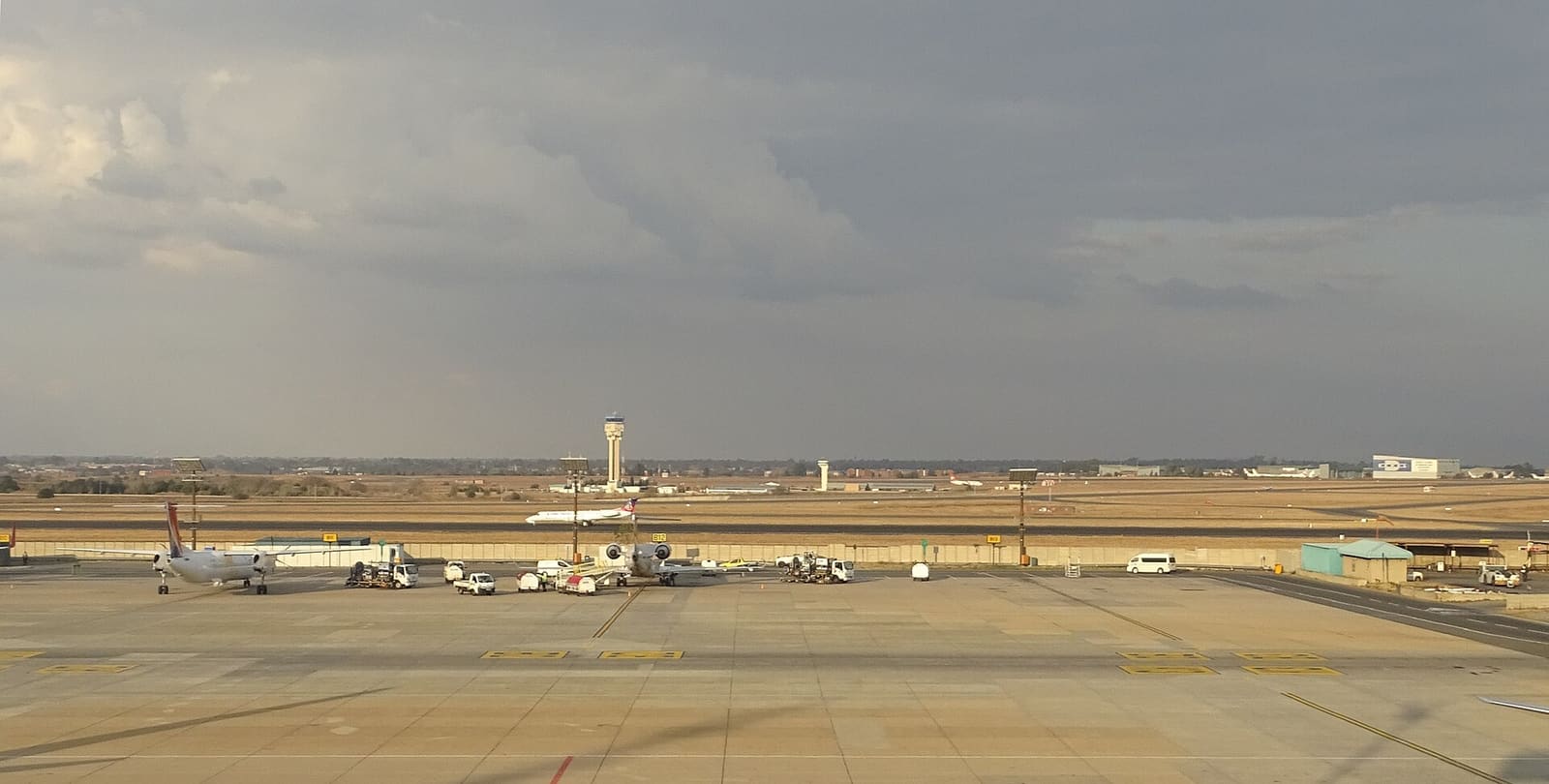 The air traffic control tower at O.R. Tambo International Airport under a cloudy sky